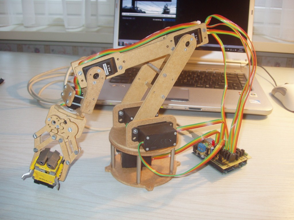 Płytka Arduino podłączona do serwomotorów z kablami i zasilaczem na stole