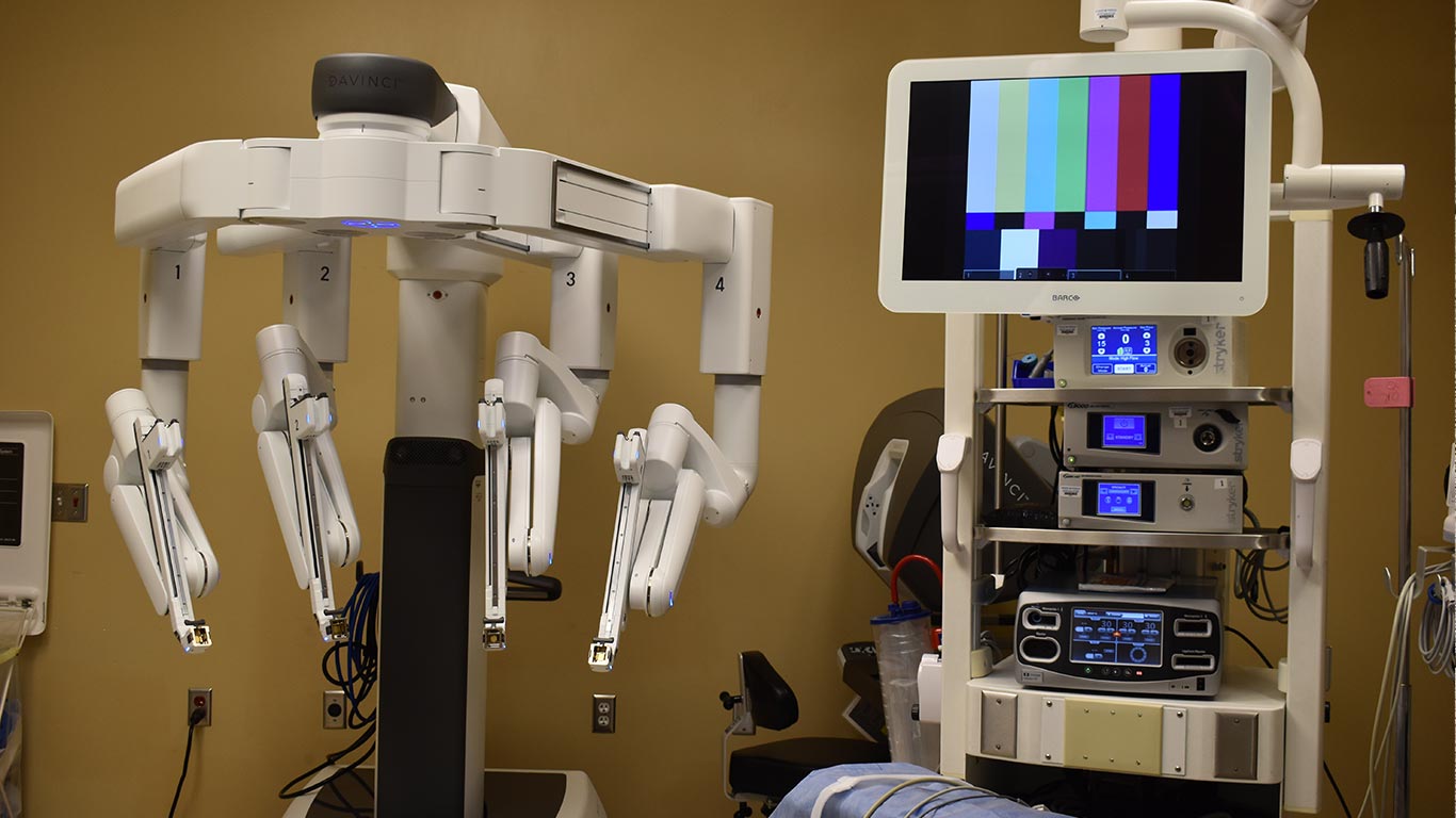 Robot chirurgiczny da Vinci z czterema ramionami i konsolą w jasnej sali operacyjnej